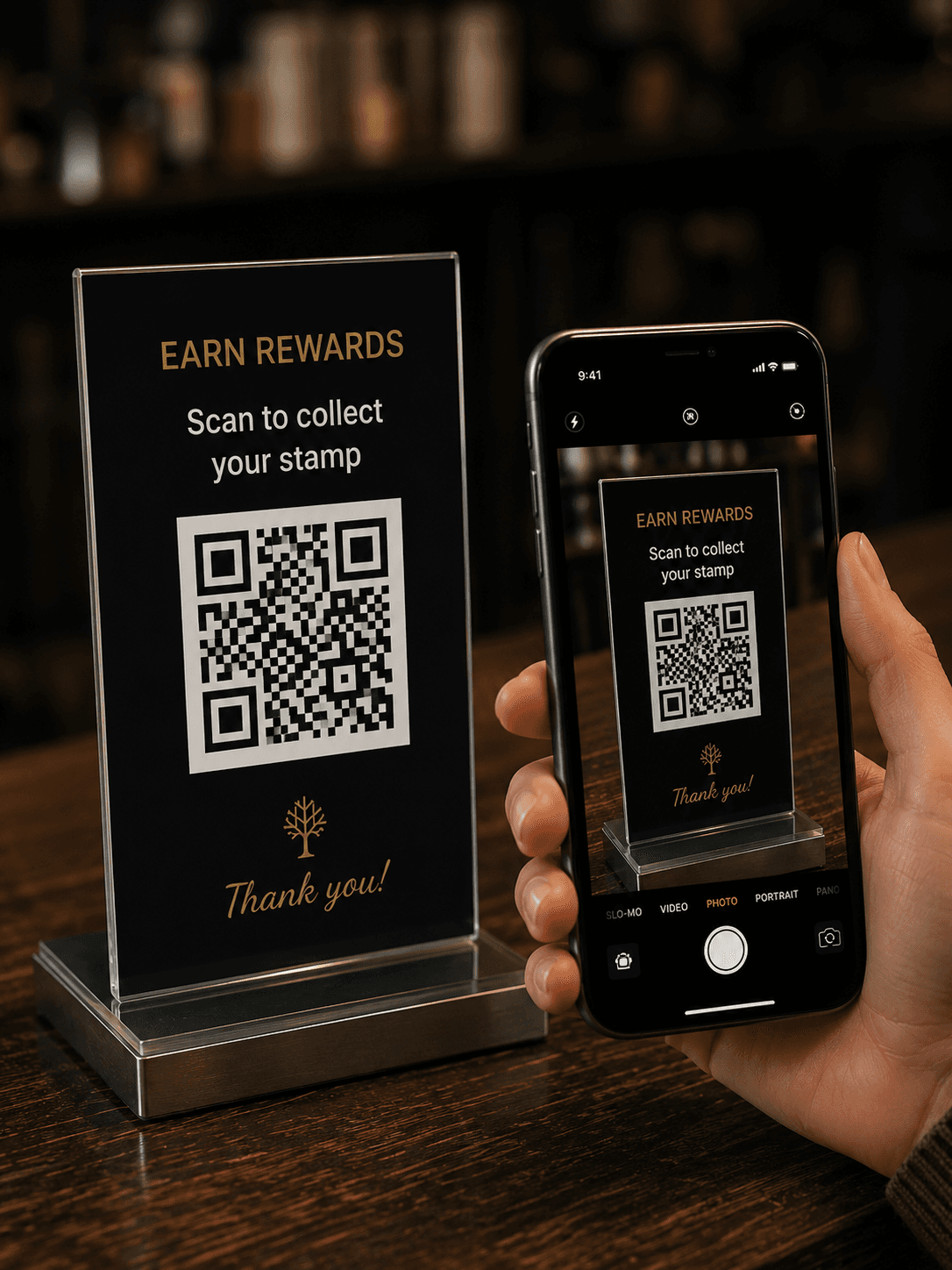 Kunde hält sein Handy neben den Qafey-QR-Ständer „Prämien sammeln“ auf einer Café-Theke und erfasst ihn im Kamerasucher.